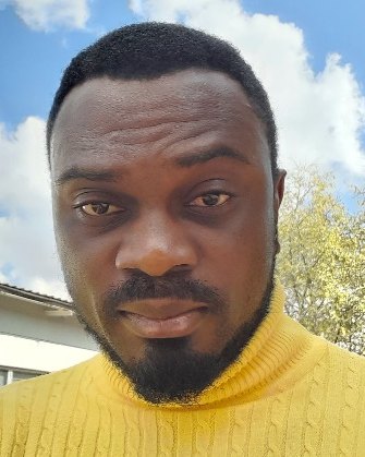 Dr Joshua Nwabuife outdoors, wearing a yellow turtleneck.