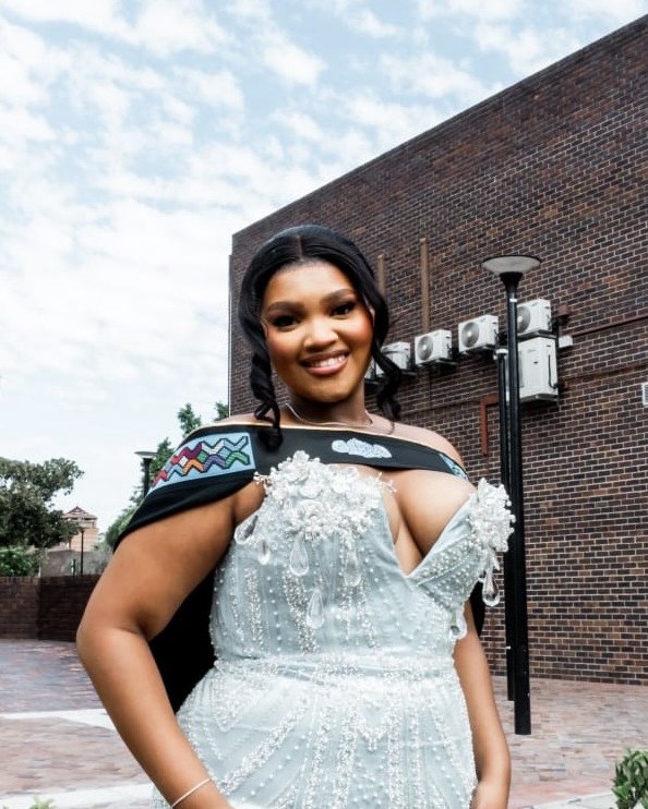 Simamkele Tempi in graduation dress, outdoors.