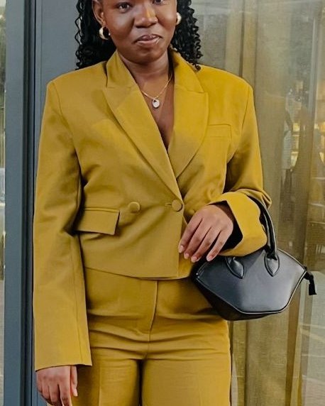 Tsima Thapelo Caroline in a mustard suit, standing outdoors.